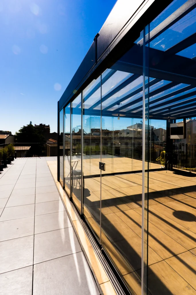 Terrazza vetrata di L.E.M. con pavimentazione in legno e pietra, cielo sereno sullo sfondo