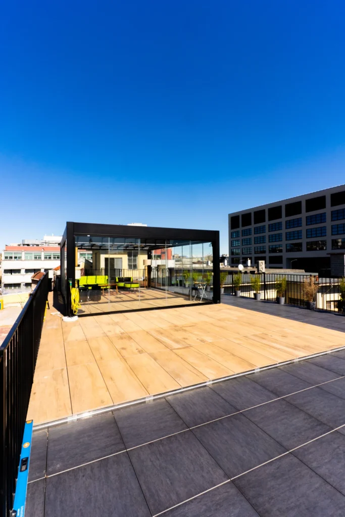 Terrazza panoramica di L.E.M. con pavimento in legno, struttura in vetro e skyline di Milano sullo sfondo